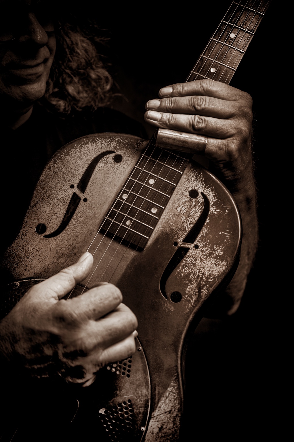 Close photograph of the Delta Boy’s hands playing resonator guitar